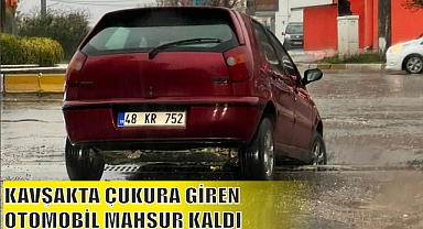 KAVŞAKTA ÇUKURA GİREN OTOMOBİL MAHSUR KALDI